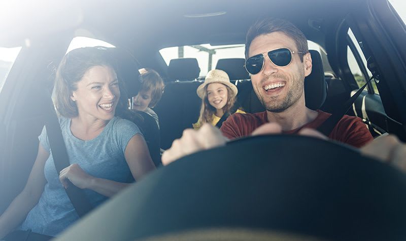 Looking through the windscreen at a man driving his Mazda with wife and kids on board
