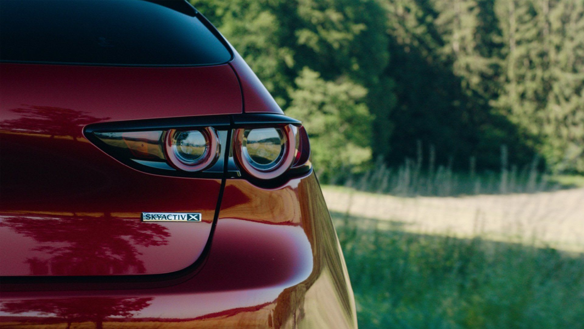 Rear view of the tail lights and Skyactiv-X badge on a red Mazda