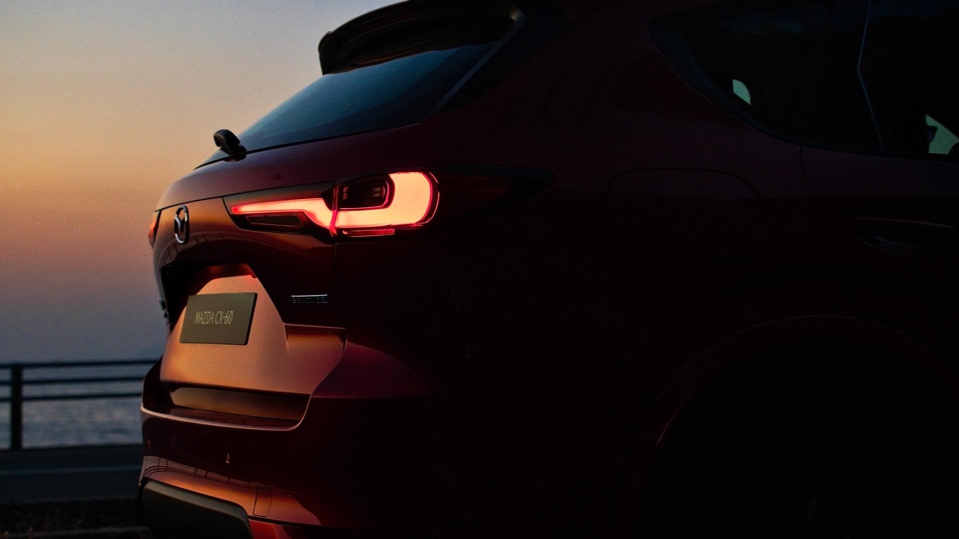 Silhouette of the rear half of a red Mazda CX-60 SUV taken at sunset