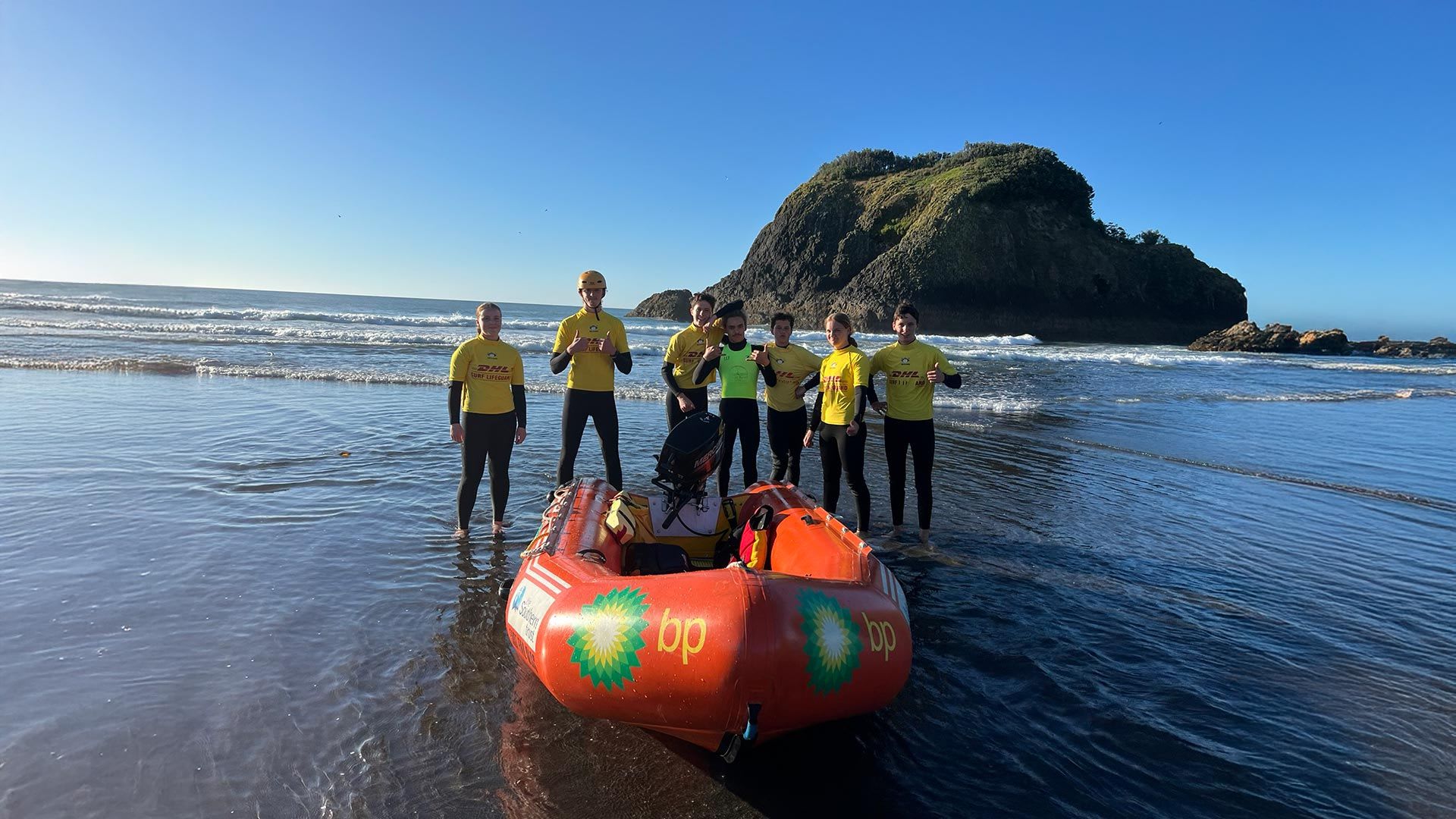 Junior surf life savers standing behind an inflatable rescue boat at a beach