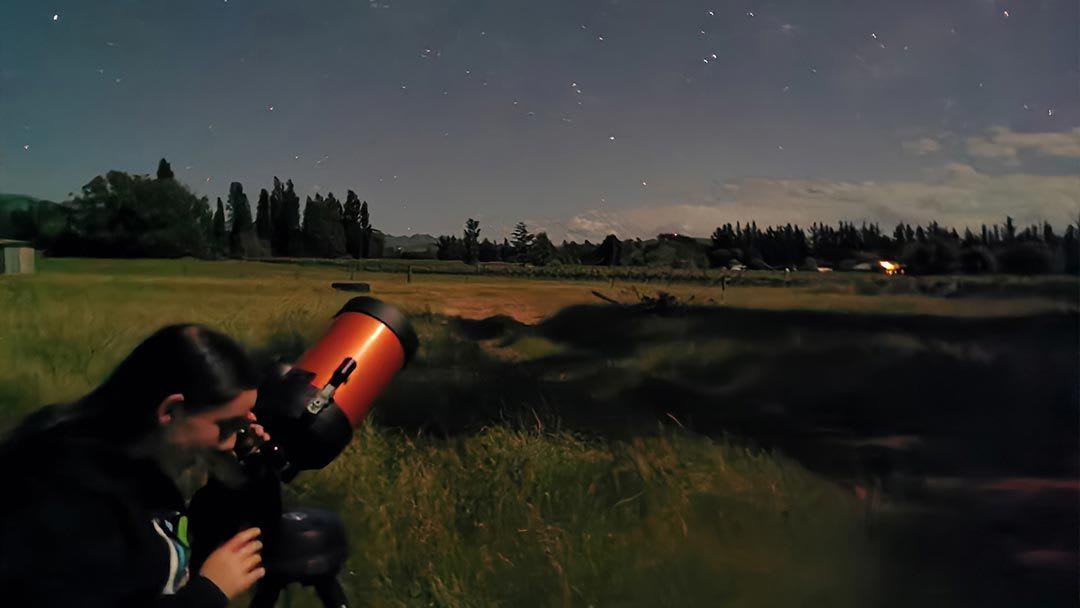 Woman looking through a telescope at the wide open sky - Mazda Foundation 2021 grant recipients