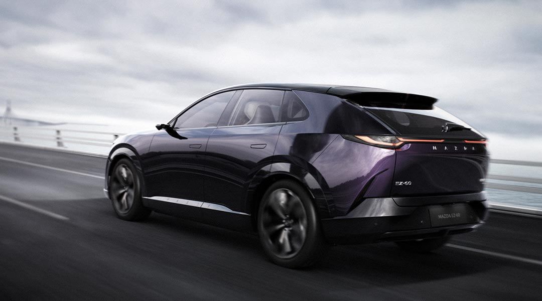 Rear three quarter view of a purple Mazda EZ-60 electric SUV driving on a freeway