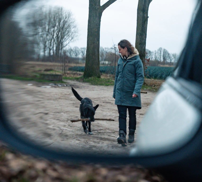 View through a Mazda's door mirror at a woman walking with her dog 