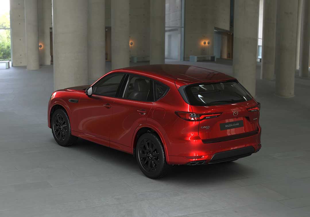 Rear three quarter view of a Soul Red Mazda CX-60 SUV SP Hybrid parked in a gallery