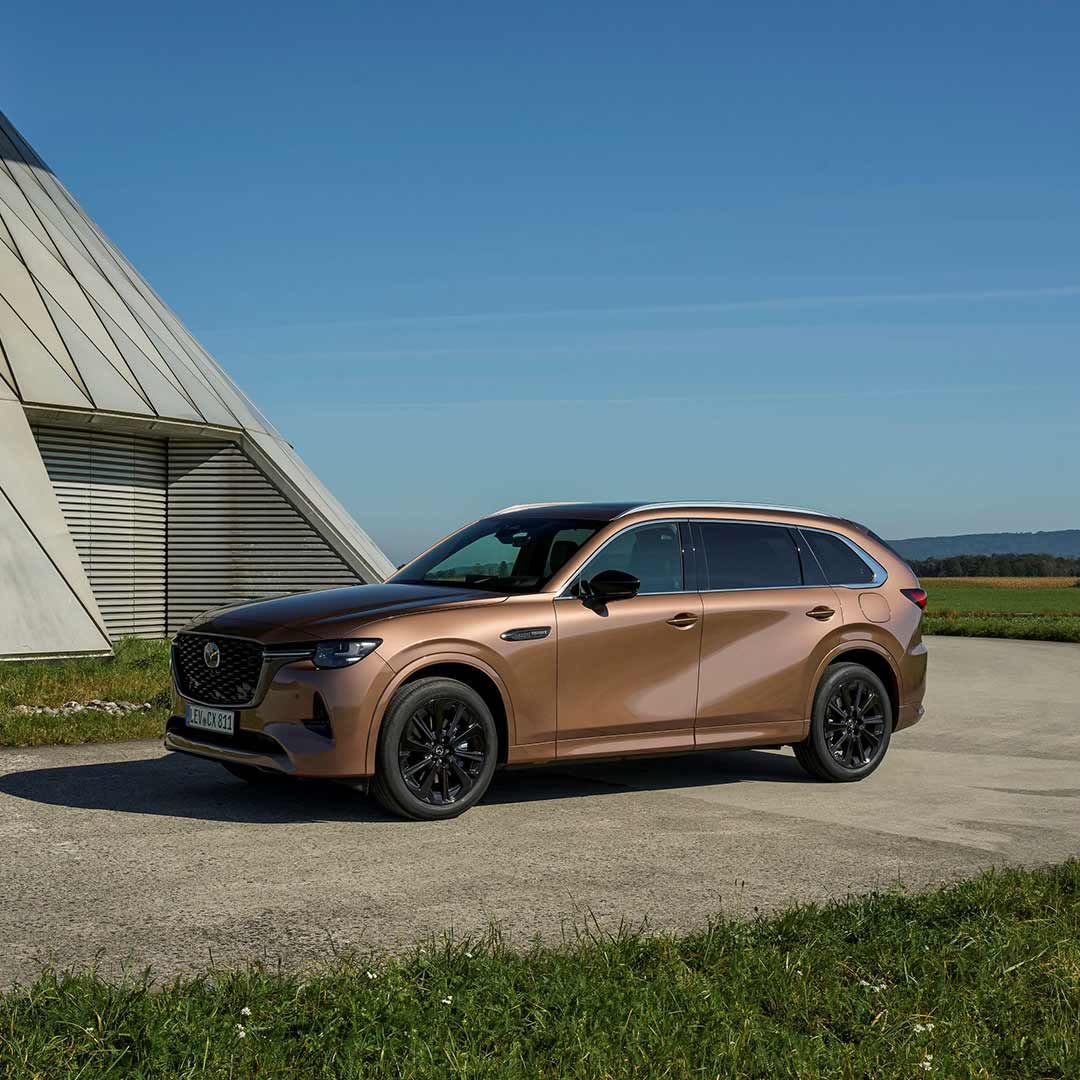 Front three quarter view of a Melting Copper Mazda CX-80 SUV parked in the open