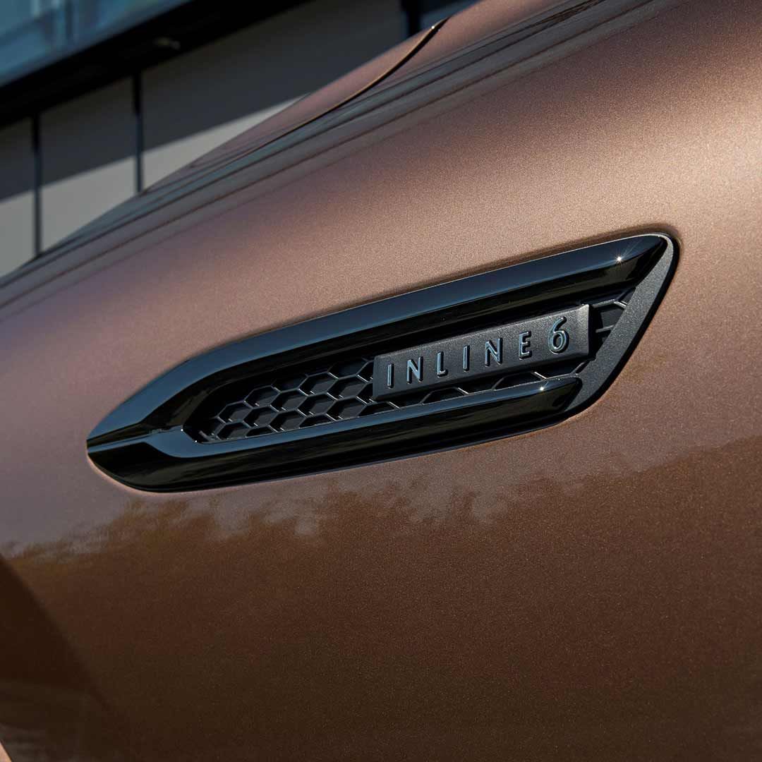 Close up of the side grille with 'inline 6' badging on a Melting Copper Mazda CX-80 Hybrid SUV