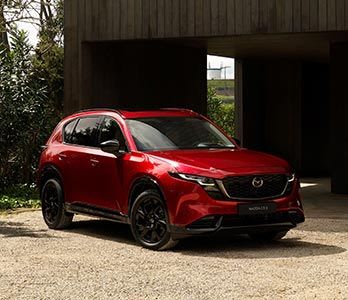 Front three quarter view of a red all-new Mazda CX-5 SUV parked on a driveway