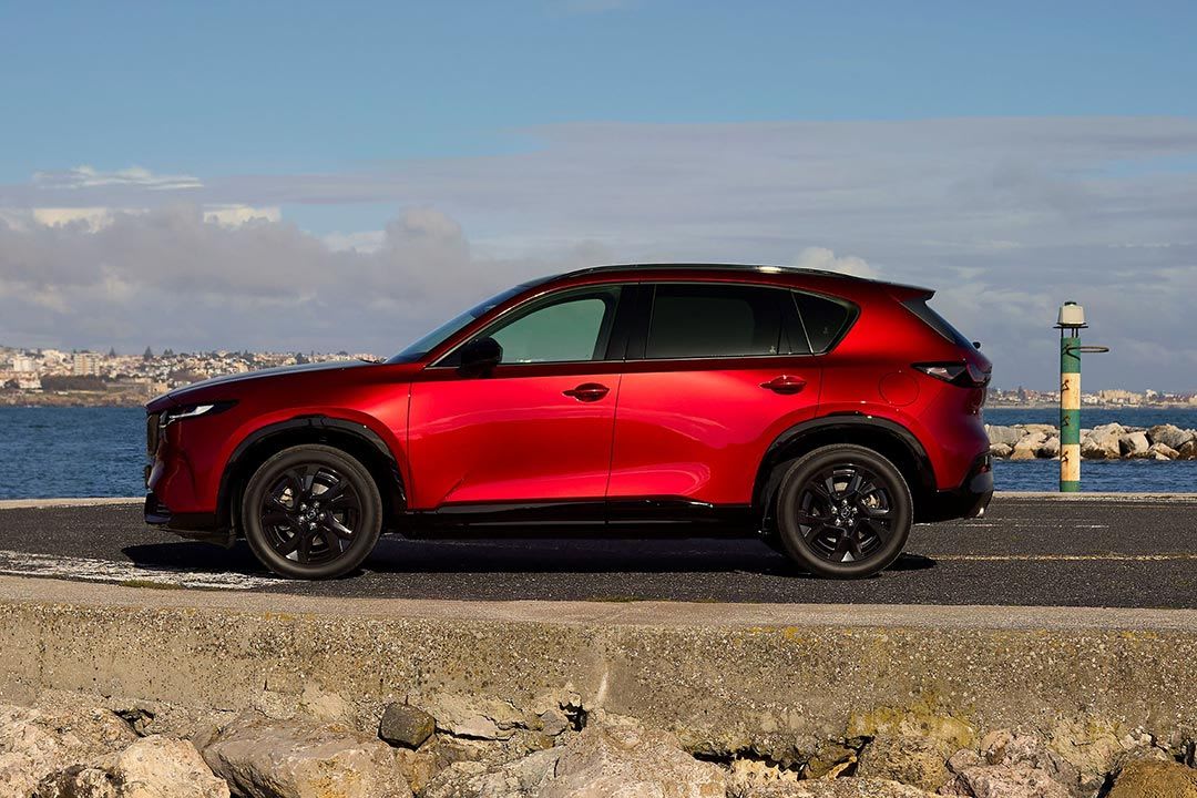 Side view of a red all-new Mazda CX-5 SUV parked on a road