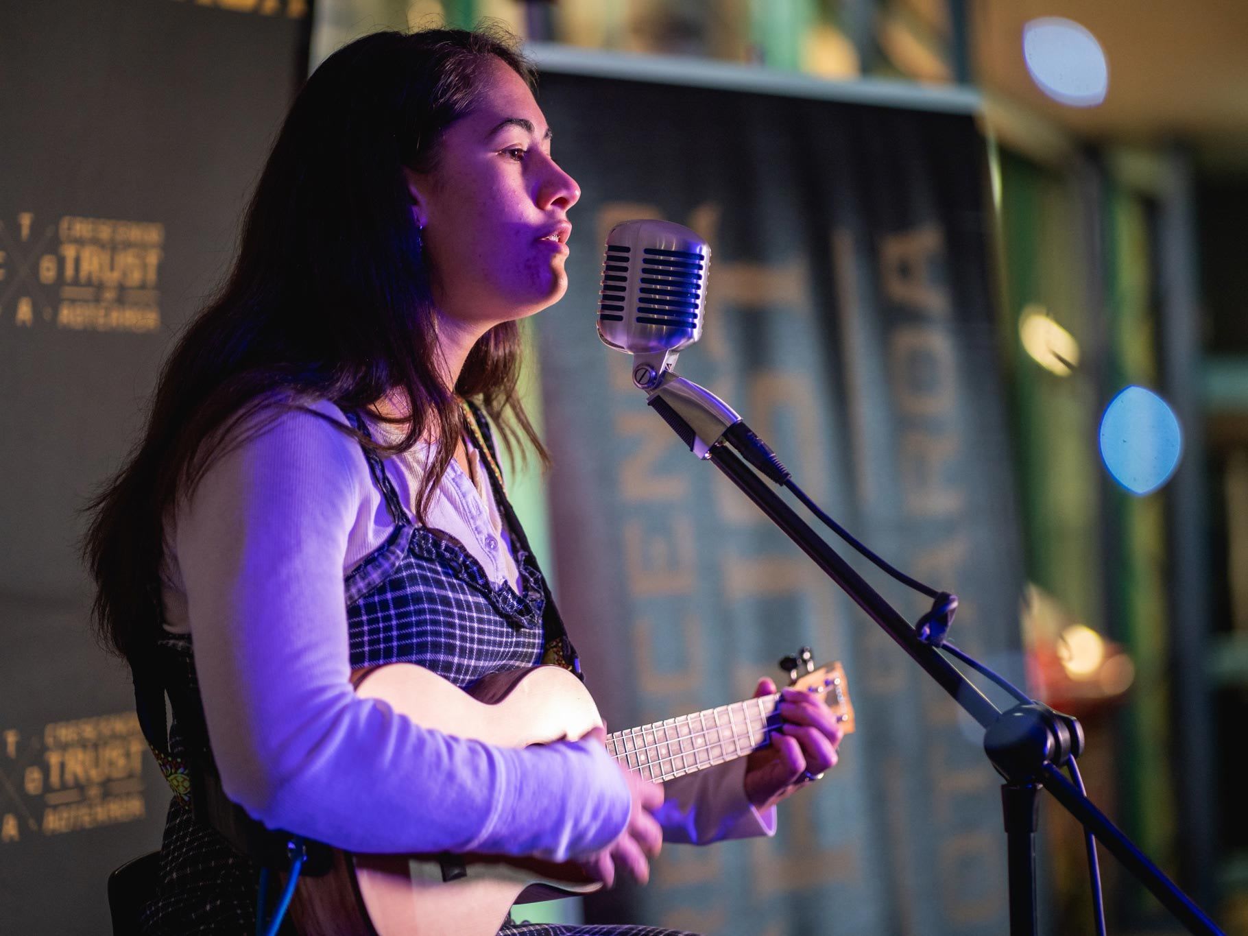 Woman singing and playing guitar at an open mike night