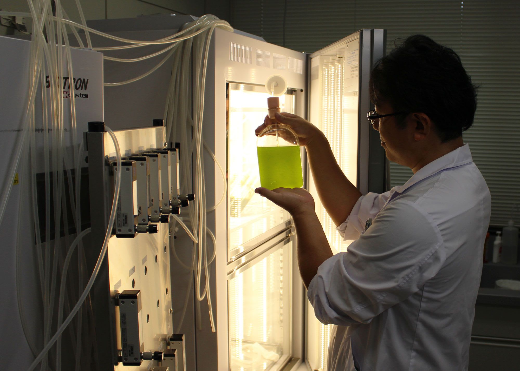 Female scientist in a lab holding a glass jar of eco fuel