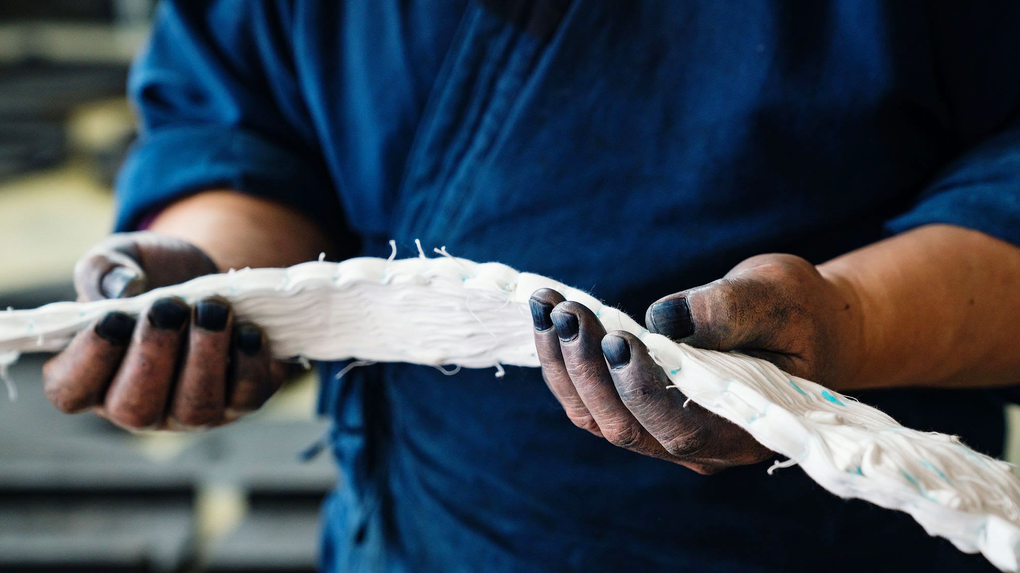 Man in a blue shirt holding white textile material in his hands