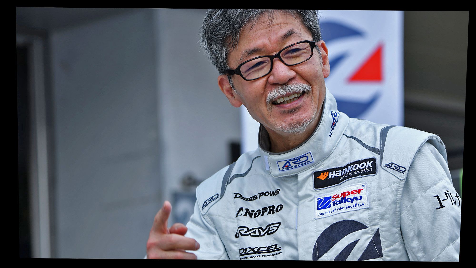 Portrait photo of Ikuo Maeda, Senior Fellow Brand Design, in a racing driver suit