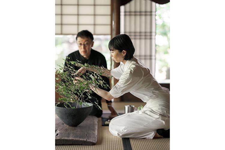 Woman tending to her potted plant as a man watches on