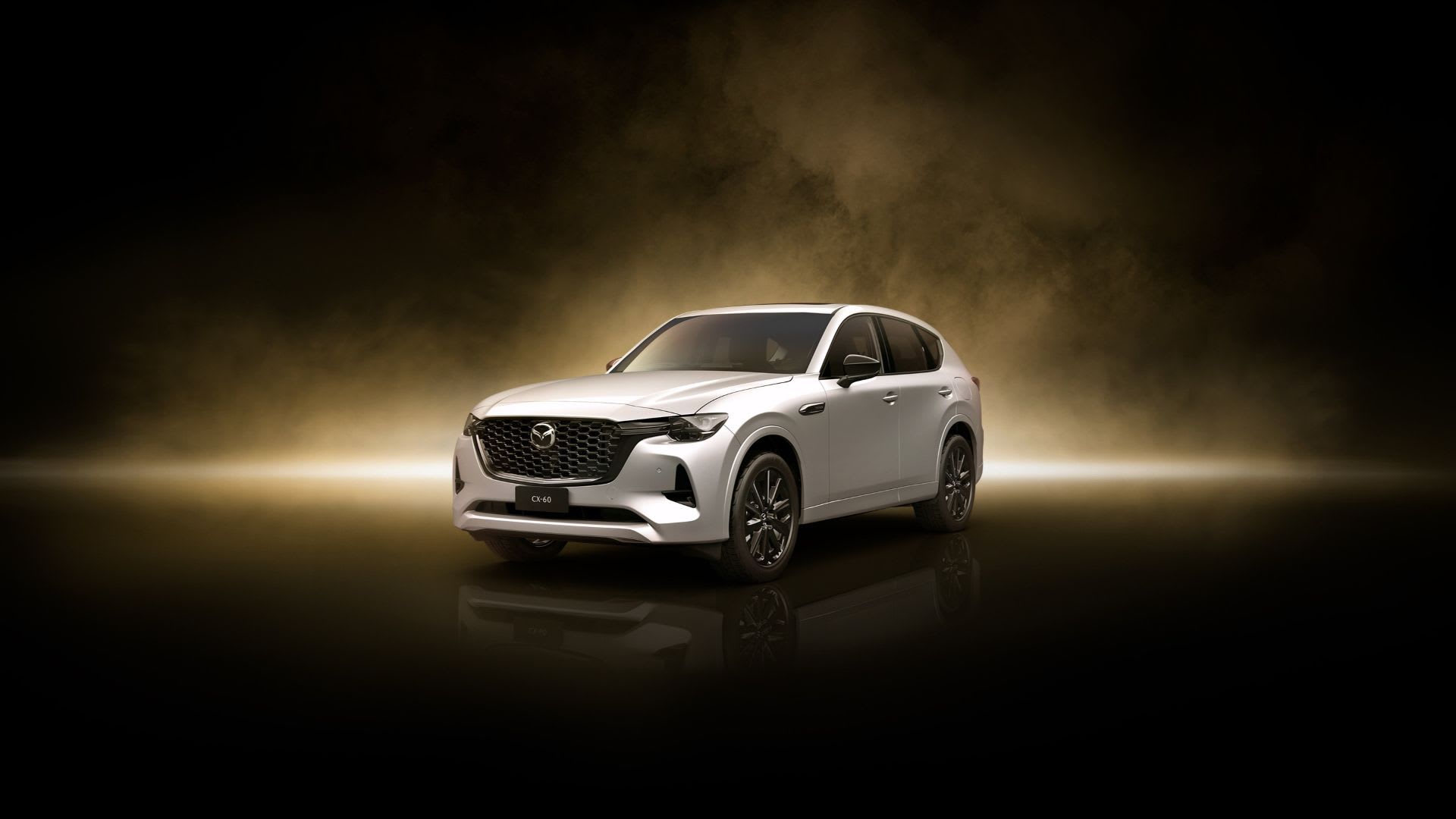 A front three-quarter image of a CX-60 Plug-In Hybrid in Rhodium White Metallic, against a gold-tinted background