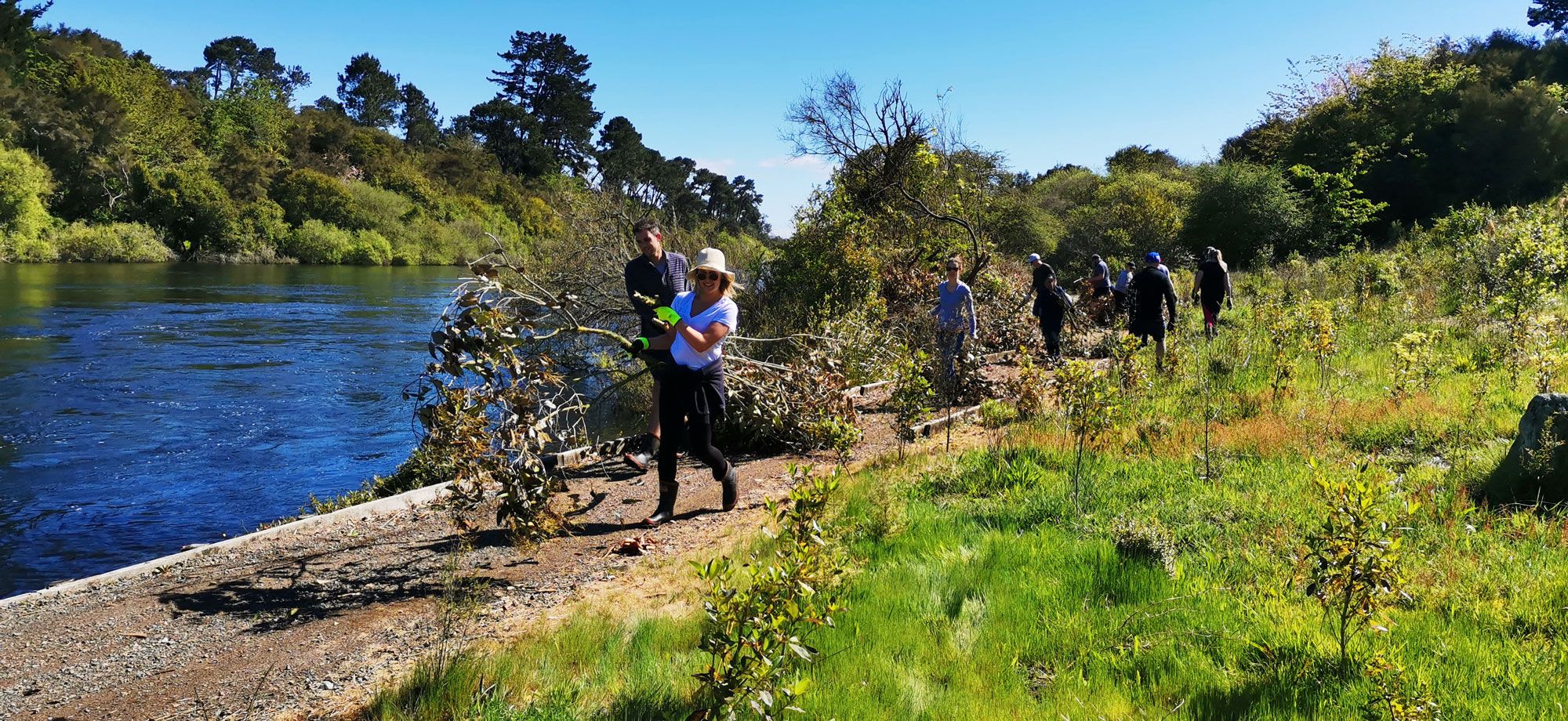 A group of walkers on a walking trail next to a river