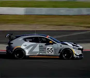 Side view of a grey Mazda3 race car on a race track in Japan