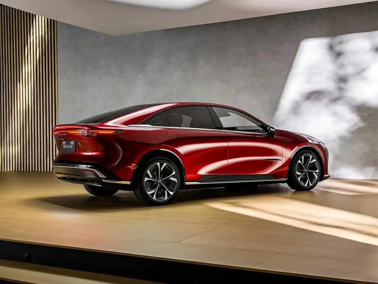 Rear three quarter view of a fully electric red Mazda 6e on display