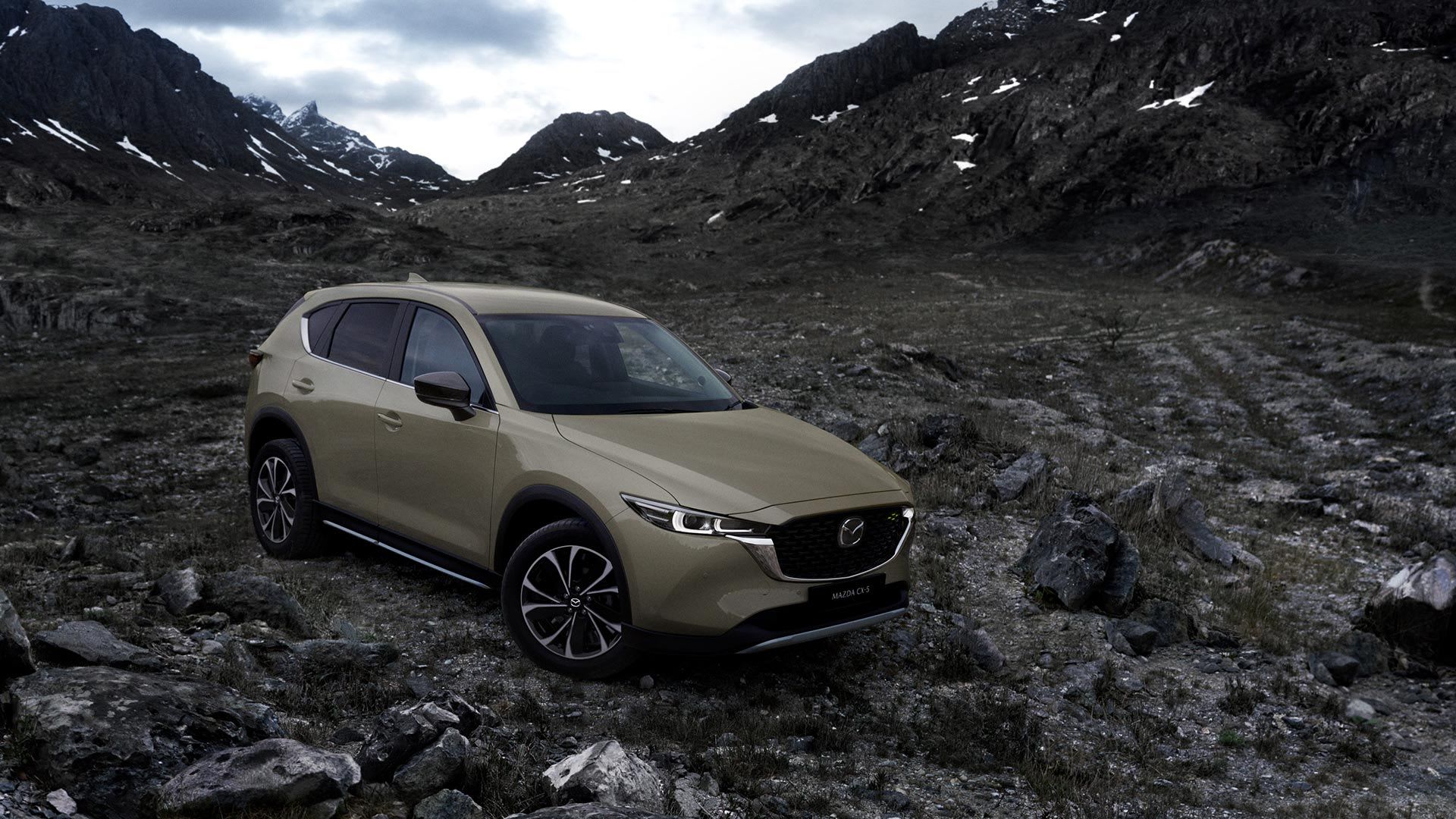 Front three quarter view of a Zircon Sand Mazda CX-5 SUV parked on a rocky outcrop