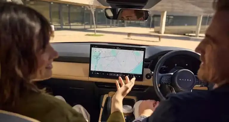Man and woman sitting in a Mazda CX-5 SUV with the centre touchscreen displaying Google Maps