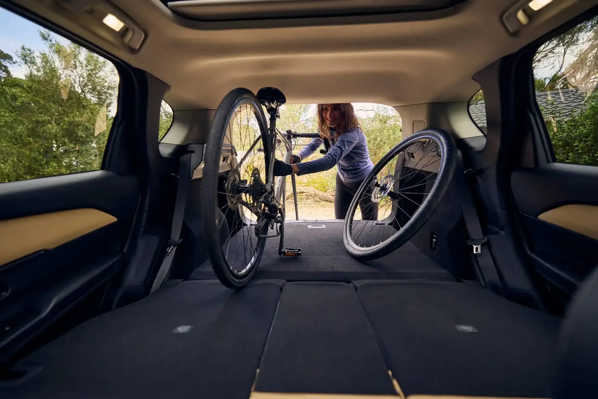 Interior view of the boot of a Mazda CX-5 SUV with a woman loading a mountain bike
