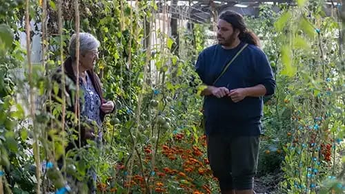 Man and woman standing and talking inside a greenhouse