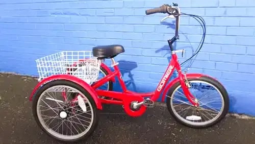 Red tricycle parked against a blue painted brick wall