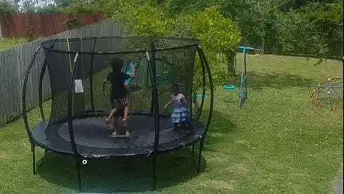 Kids playing in a backyard trampoline
