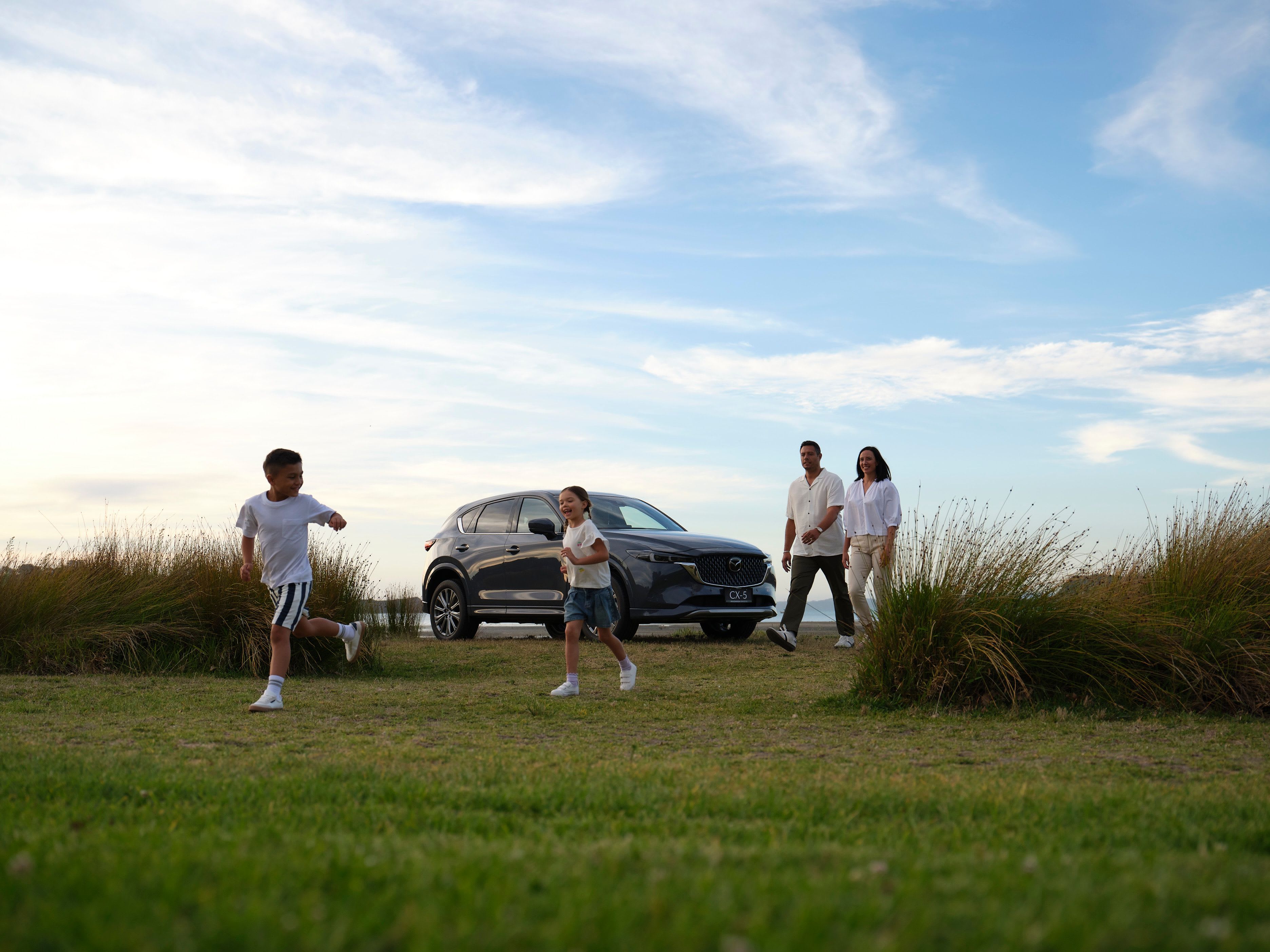 Family going for an evening walk after parking their Mazda CX-5 in Machine Grey Metallic