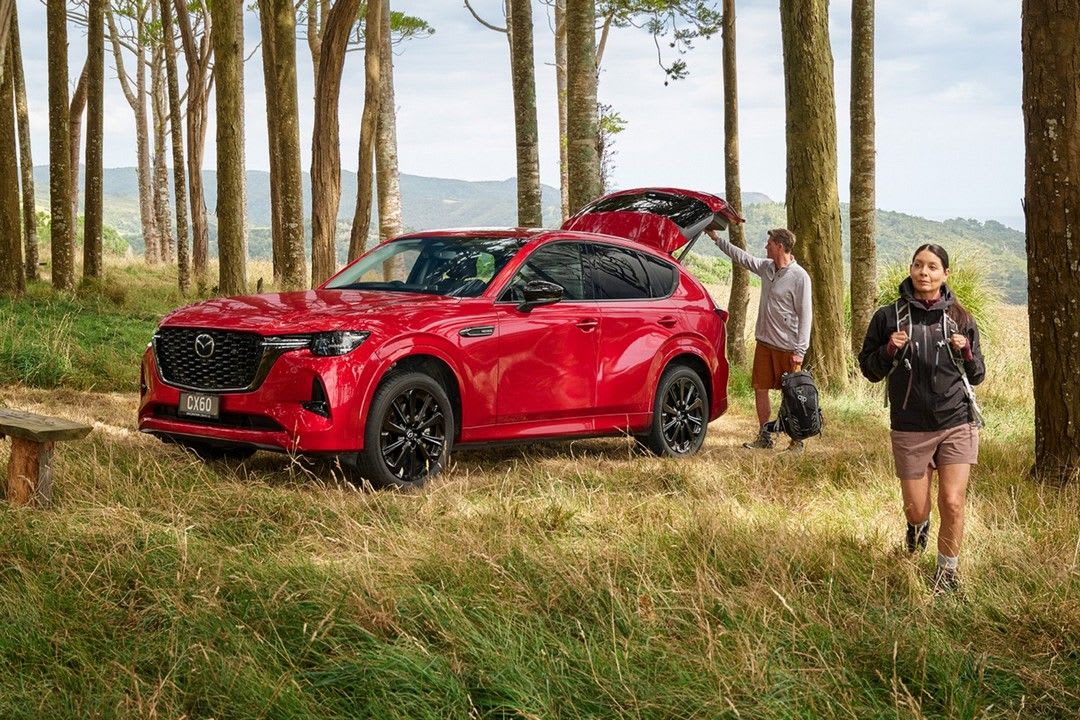 Two people getting out of their Soul Crystal Red Metallic Mazda CX-60 to go for a walk in the countryside