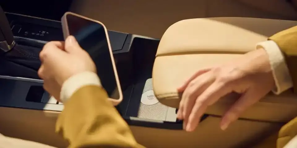 Close up of a passenger in a Mazda CX-5 SUV putting her phone into the wireless charging dock in the front centre console