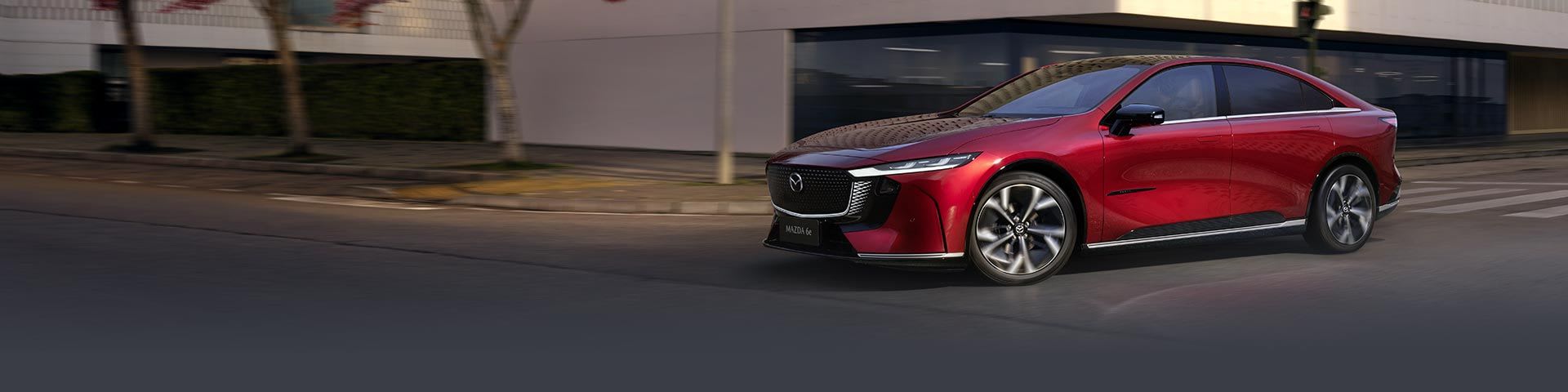 Front three quarter all-electric Soul Red Mazda 6e with impressive driving dynamics in the city
