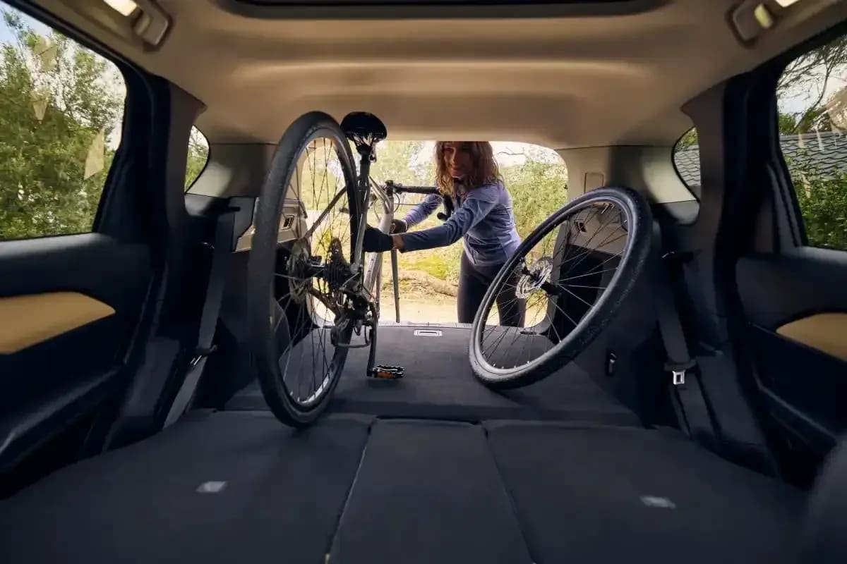 Looking back through the boot of a Mazda CX-5 with a woman loading a mountain bike into the car