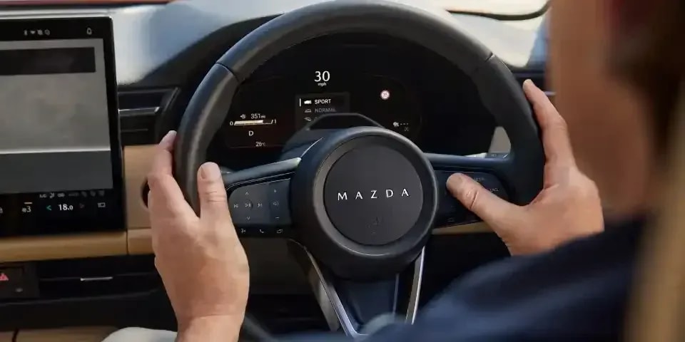 Hands gripping the steering wheel of a Mazda CX-5 SUV