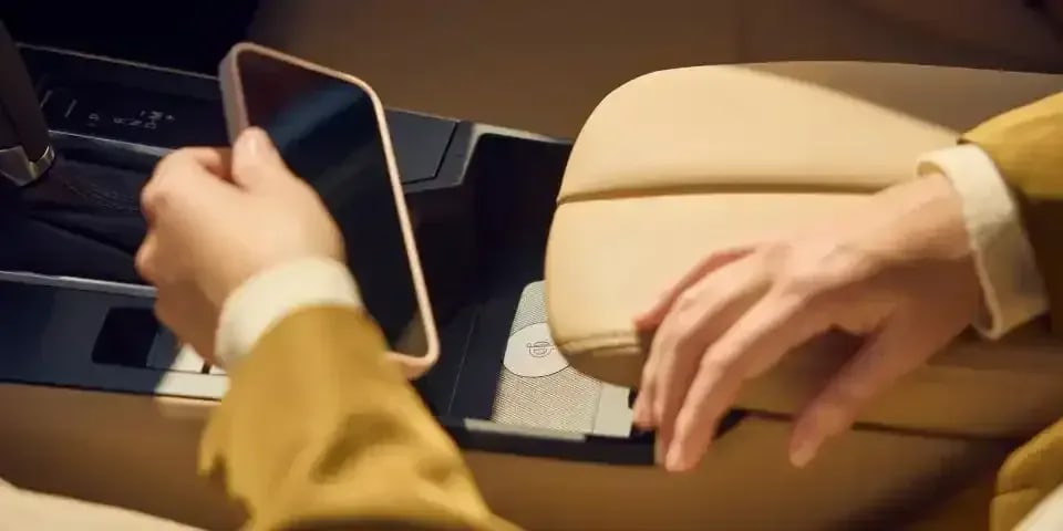 Close up of a passenger in a Mazda CX-5 SUV putting her phone into the wireless charging dock in the front centre console