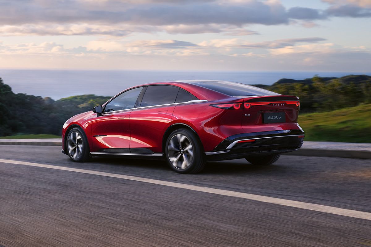 Rear three quarter view of a Soul Red all-electric Mazda 6e showing its dynamic hatchback profile