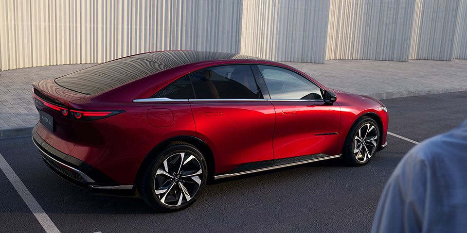 Rear three quarter view of a Soul Red all-electric Mazda 6e with frameless doors and flush door handles 
