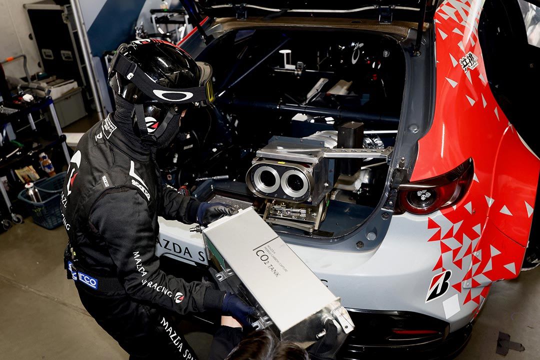 A Mazda race team mechanic replacing the C0₂ tank inside the boot of the MAZDA SPIRIT RACING 3 Future concept race car 