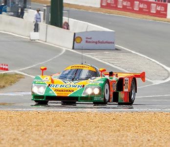Mazda 787b race car driving through turn 1 on the famous Le Mans circuit on its way to victory in 1991 
