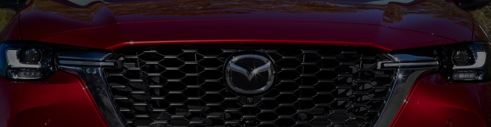 Close up of the front grille of a Soul Red Mazda CX-60 Hybrid SUV