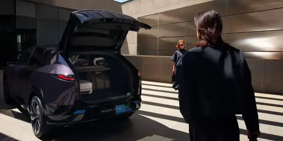 Mazda CX-6e electric SUV parked with its boot open  and a couple standing nearby 