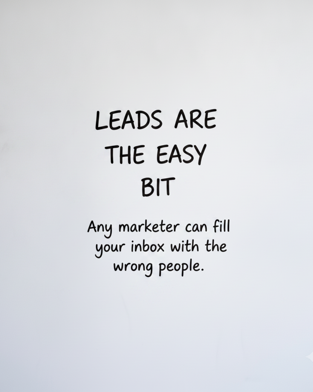 Whiteboard with the words Leads are the easy bit written in black marker with a smaller line about filling an inbox with the wrong people