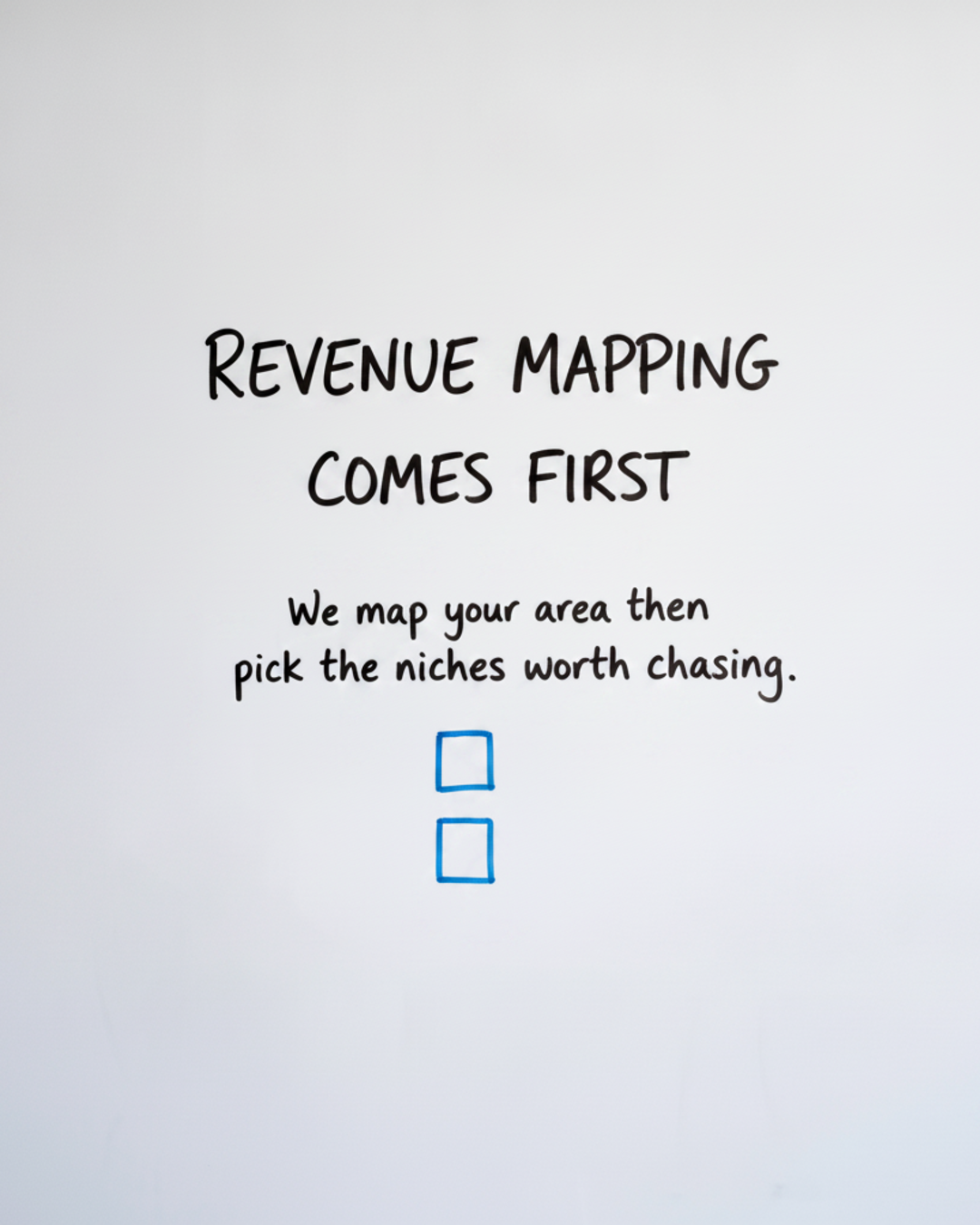 Whiteboard with the words Revenue mapping comes first written in black marker above two blue stacked boxes