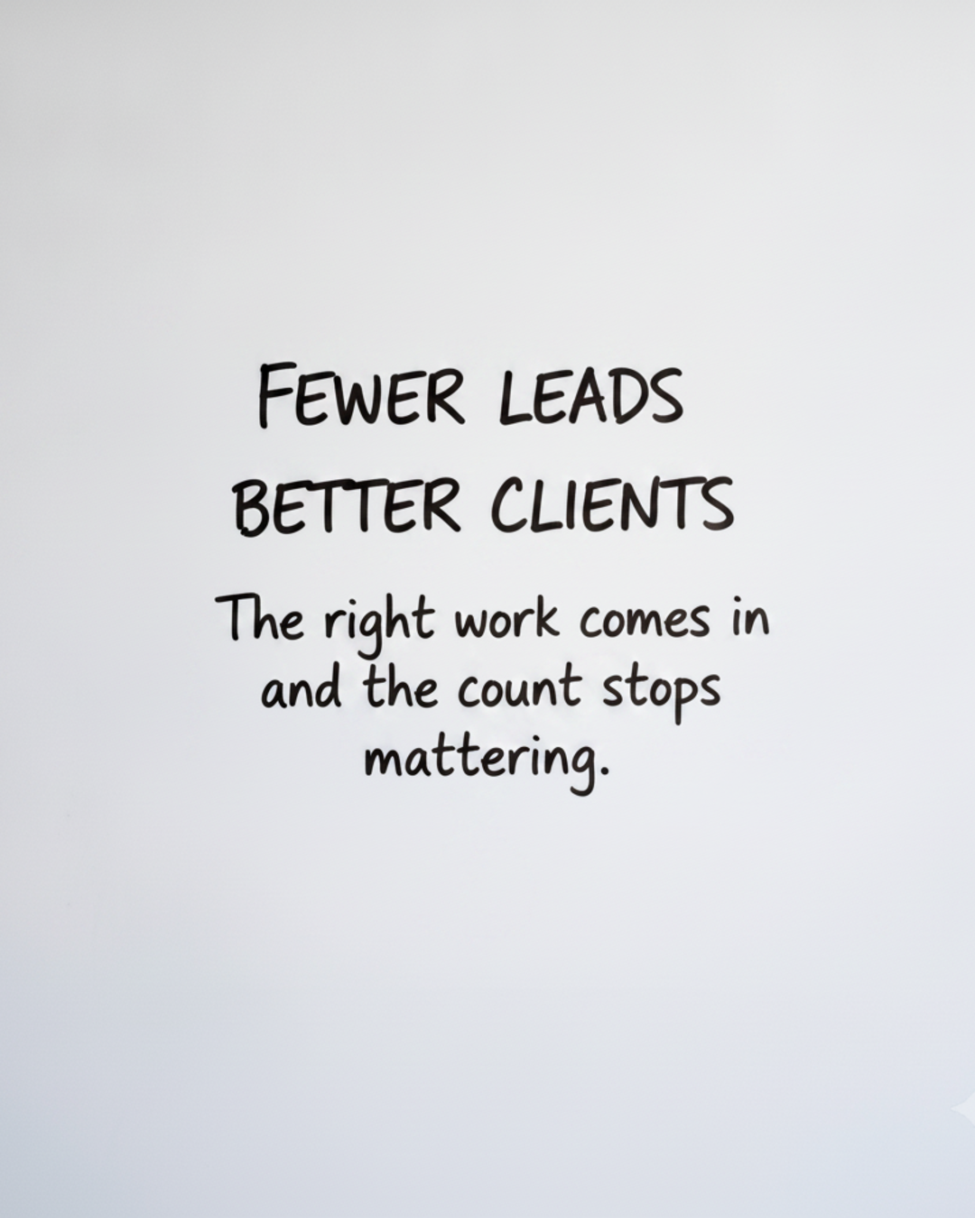 Whiteboard with the words FEWER LEADS BETTER CLIENTS written in black marker