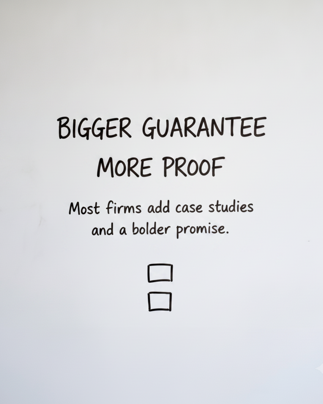 Whiteboard with the words BIGGER GUARANTEE MORE PROOF written in black marker above two stacked boxes