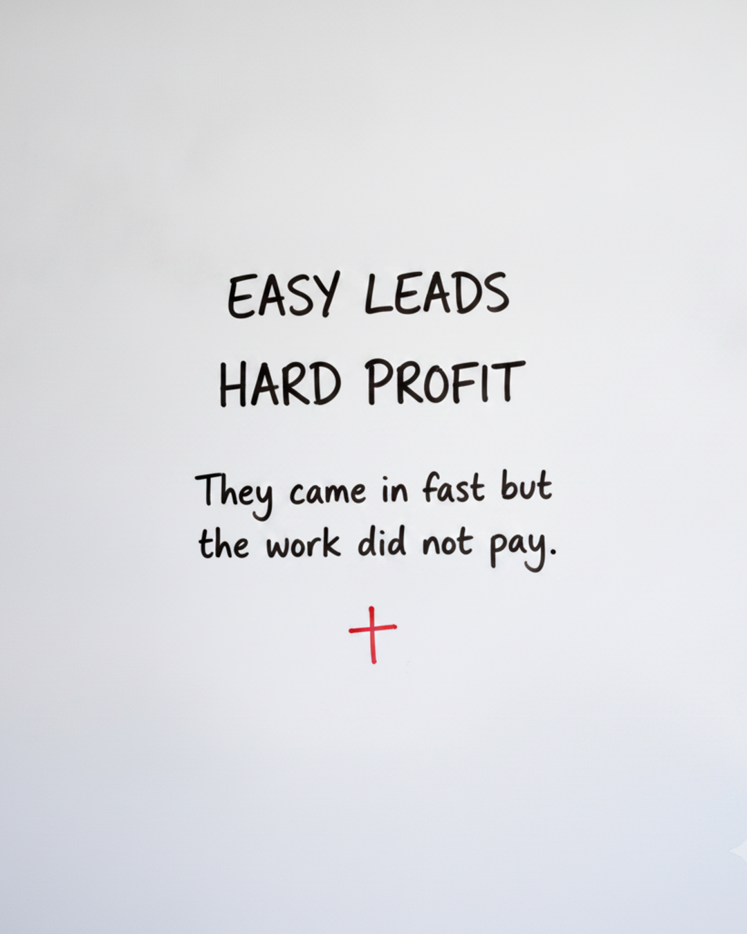 Whiteboard with the words EASY LEADS HARD PROFIT in black marker above a small red cross