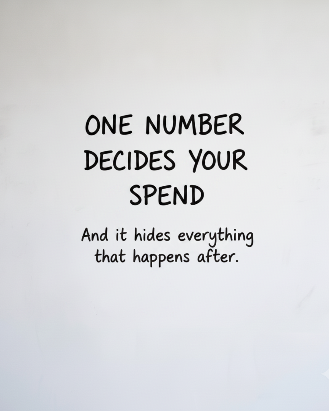 Whiteboard with the words One number decides your spend written in black marker, above the line And it hides everything that happens after
