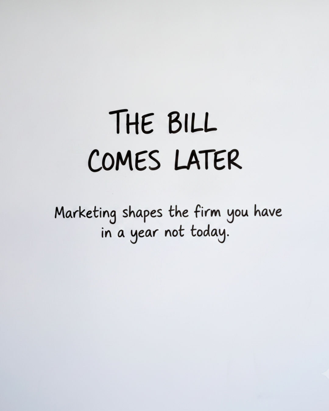 Whiteboard with the words THE BILL COMES LATER written in black marker
