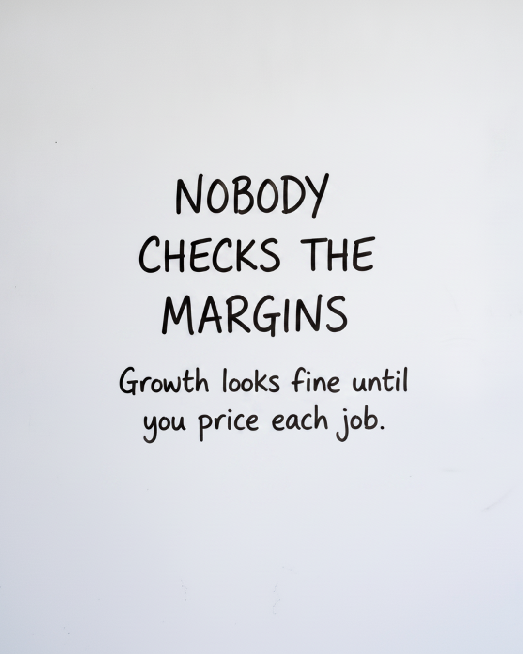 Whiteboard with the words Nobody checks the margins written in black marker with a smaller line about pricing each job