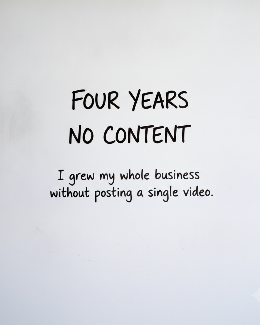 Whiteboard with the words FOUR YEARS NO CONTENT written in black marker above the line I grew my whole business without posting a single video
