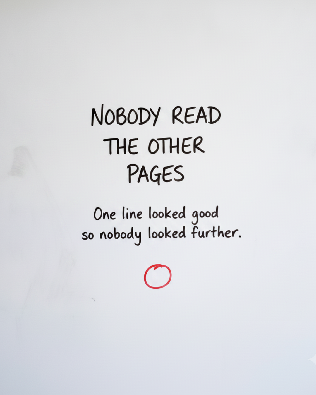 Whiteboard with the words Nobody read the other pages written in black marker, above a small circle drawn in red